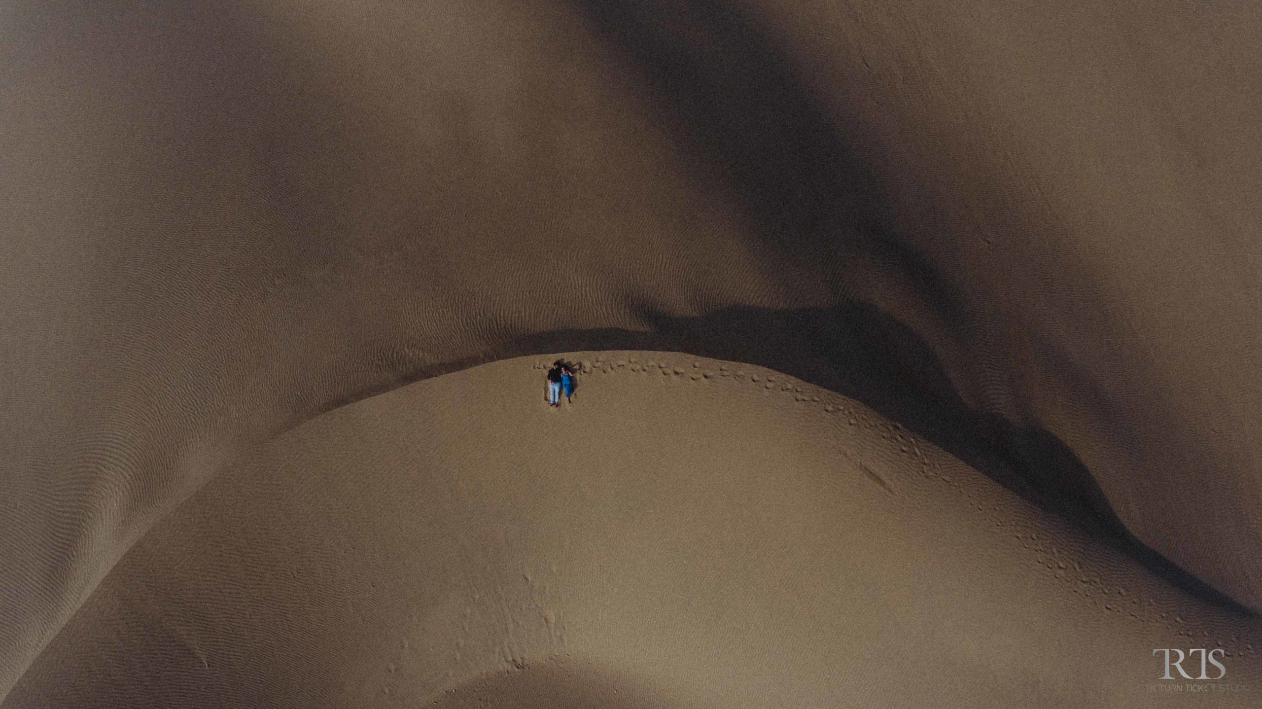 aerial/drone shot in the jaisalmer desert girl wearing blue dress